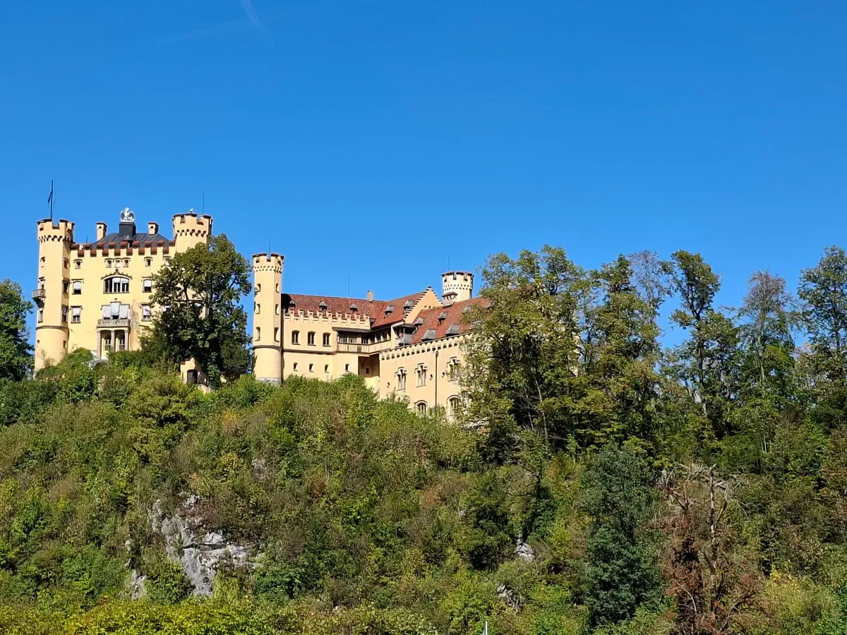 Hohenschwangau Castle on its wooded hill below Neuschwanstein, seen on a Neuschwanstein castle tour from Munich, Bavaria